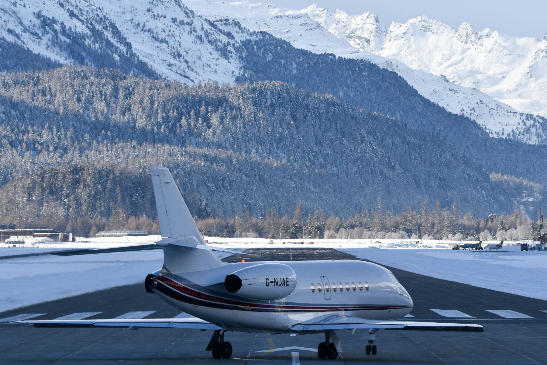 Private jet taxiing on a snow-lined alpine runway