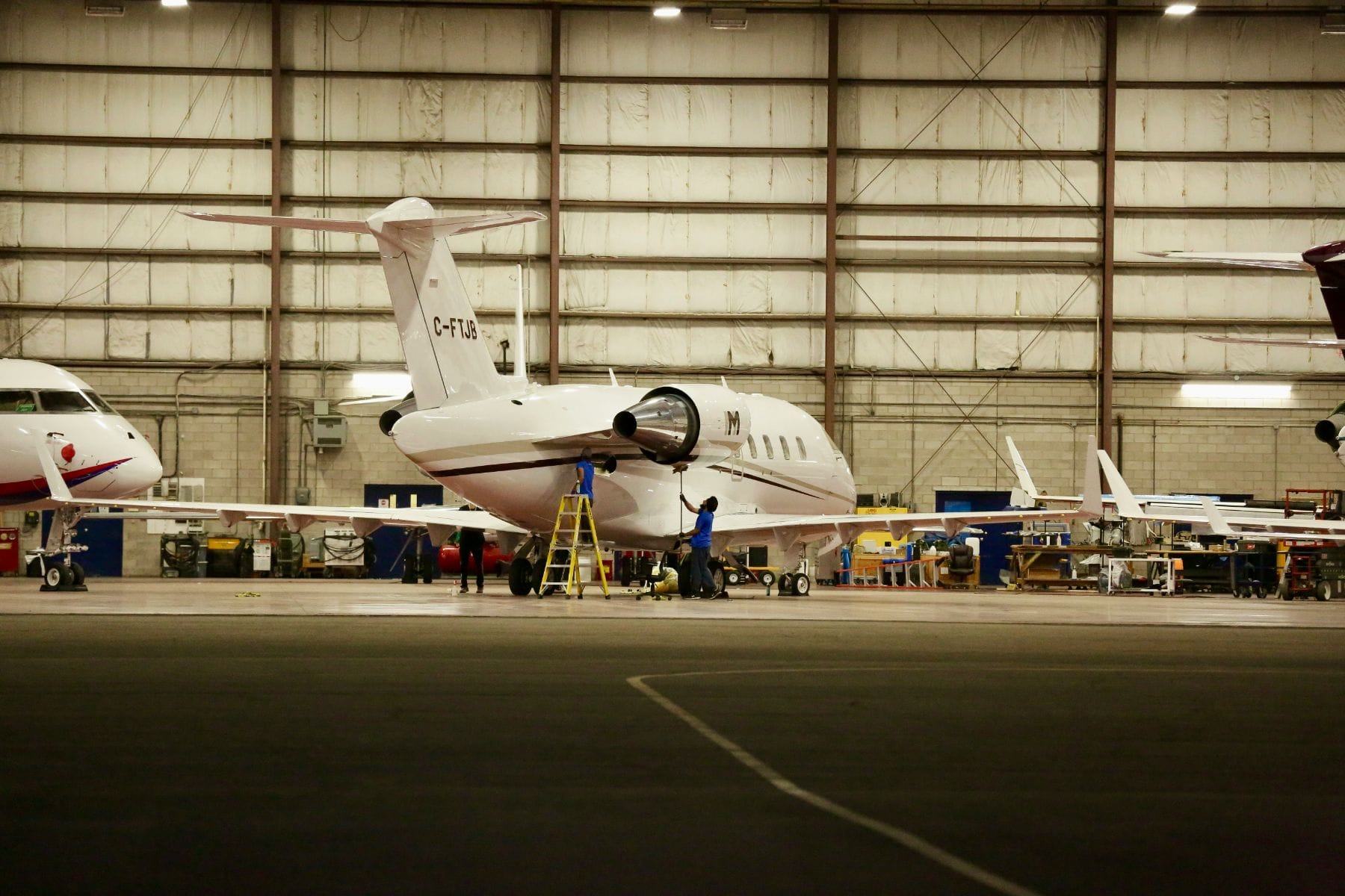 Maintenance technicians working on a private jet inside a hangar